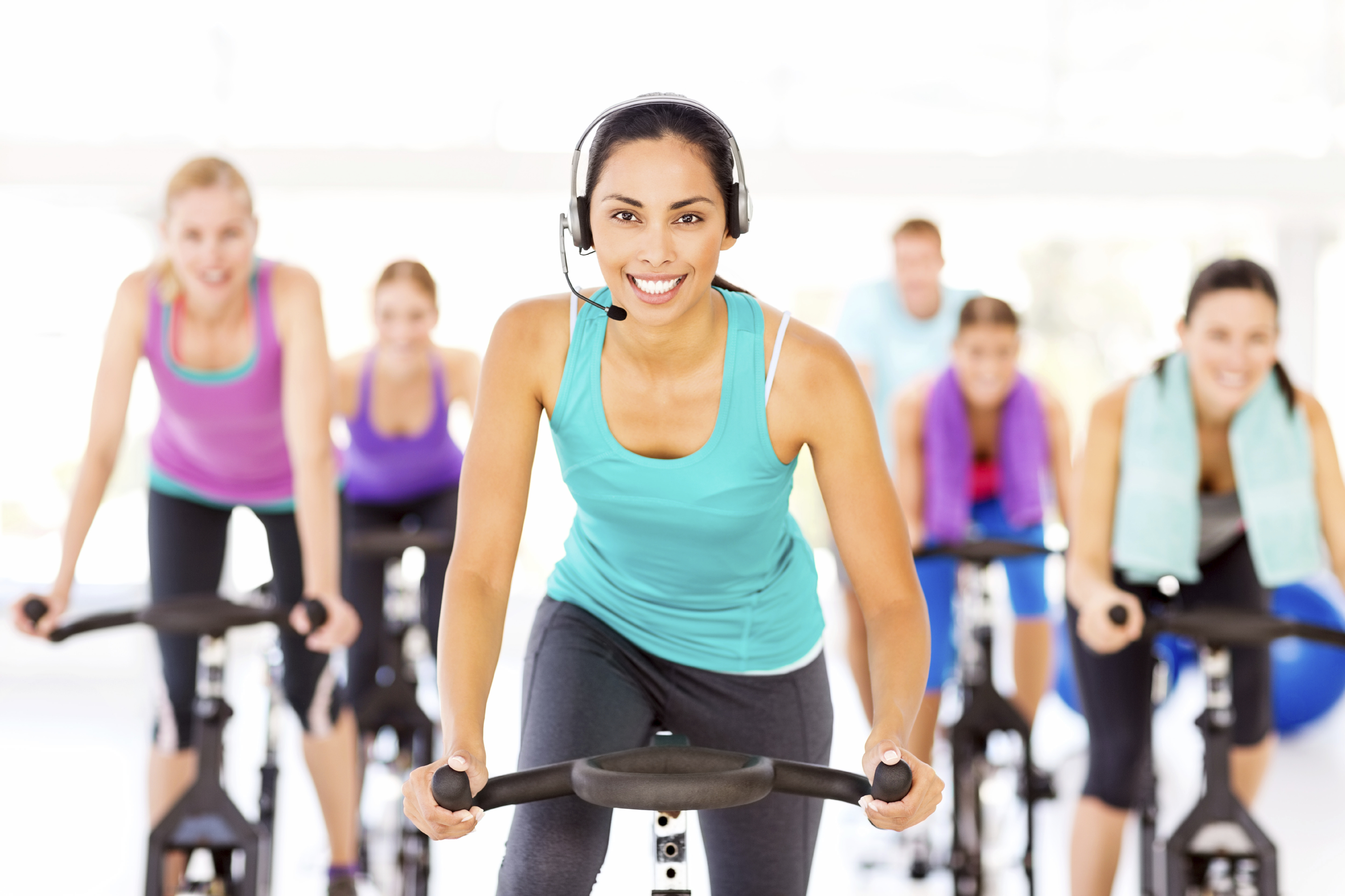 Professional Female Fitness Instructor Wearing A Headset Instructing Bicycle Fitness Class