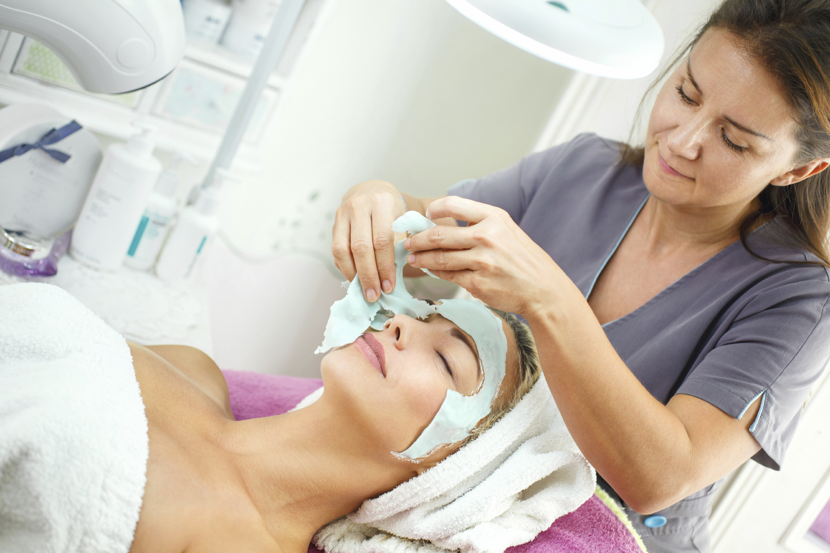 Professional Female Esthetician Removing Facial Mask From Female Client